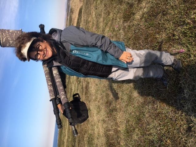 JoAnne Fillatti standing in a field carrying photography equipment